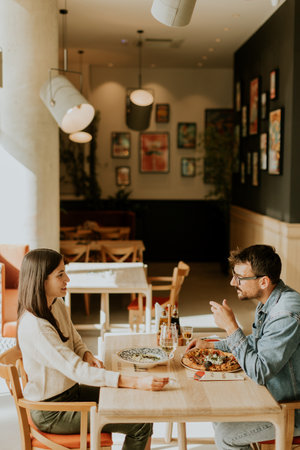 Young couple share a heartfelt moment at a cafÃ©, smiling and holding hands over drinks while surrounded by a charming and artistic atmosphere.の写真素材
