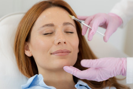 Client sits comfortably in a bright clinic, smiling as a professional applies dermal filler treatment. The serene atmosphere supports relaxation and rejuvenation.の写真素材