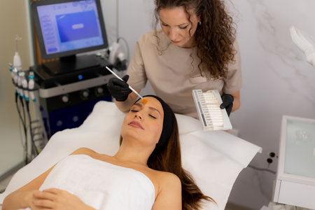 A beauty therapist applies a rejuvenating cream to a client's face, aiming to enhance moisture and reduce wrinkles. The treatment unfolds in a tranquil salon environment.の写真素材