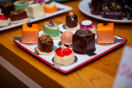 A colorful array of artisan chocolates is elegantly presented on a stylish plate during a joyful confectionery event. Each piece is crafted with unique flavors and artistic designs.の写真素材
