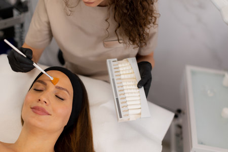 A beauty therapist applies a rejuvenating cream to a client's face, aiming to enhance moisture and reduce wrinkles. The treatment unfolds in a tranquil salon environment.の写真素材