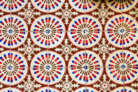Vibrant azulejos, painted with circular motifs in red, white, and blue, cover a building in Lisbon....