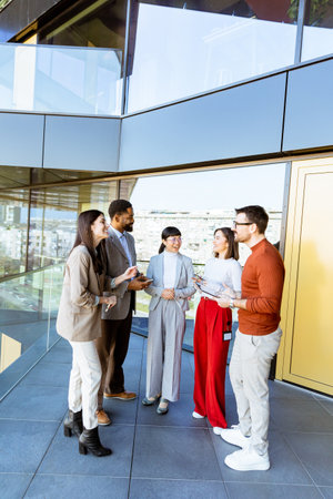 A diverse group of professionals stands in a modern office space, sharing ideas and laughter during...