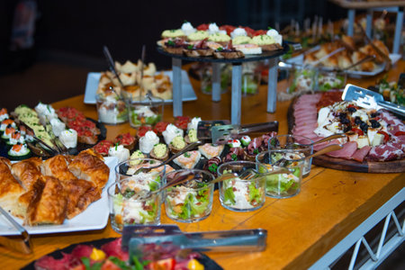 An impressive spread of canapes decorates a long table at a stylish gathering, inviting guests to...