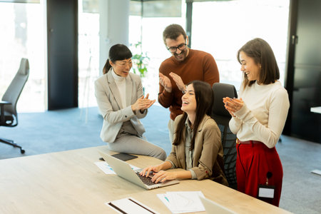 In a contemporary workspace, colleagues share smiles and applause, showing appreciation for a job well done. A successful project brings a sense of camaraderie and joy to the team.の写真素材