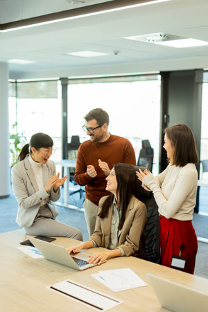 A diverse group of professionals engages in a dynamic brainstorming session. They exchange ideas, collaborate on laptops, and share documents in a bright, open workspace.の写真素材