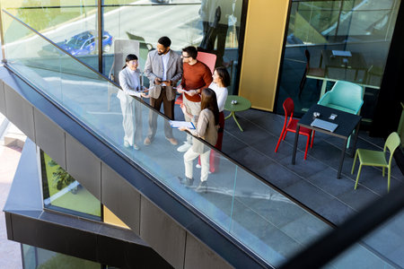 Four professionals gather on a balcony, discussing project plans while enjoying the bright sunlight.