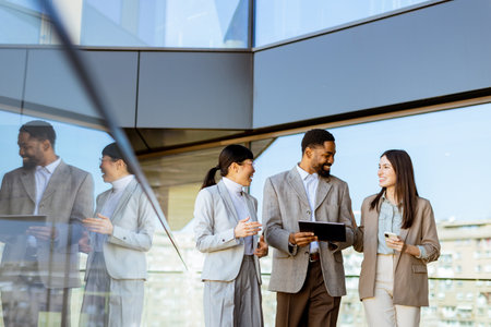Three colleagues enjoy a lively discussion while walking through a sleek, contemporary office, sharing insights and ideas, fostering teamwork, and collaboration on a sunny day.の写真素材