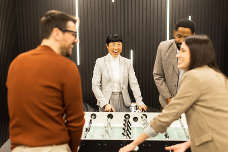 Friends gather around a sleek foosball table, their expressions filled with excitement and competition, enjoying an afternoon of fun in a stylish, contemporary setting.の写真素材
