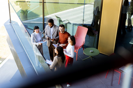 Four professionals gather on a balcony, discussing project plans while enjoying the bright sunlight.の写真素材