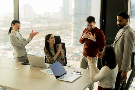 Colleagues gather in a bright, contemporary office to celebrate a successful collaboration. Smiles, handshakes, and applause fill the air, showcasing their unity and achievement.の写真素材