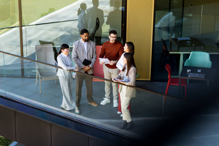 Four professionals gather on a balcony, discussing project plans while enjoying the bright sunlight.