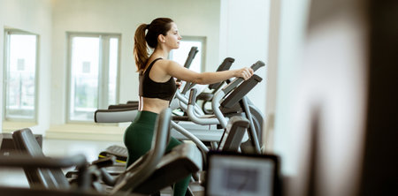 A woman engages in a focused workout on a treadmill, surrounded by bright windows in a contemporary...