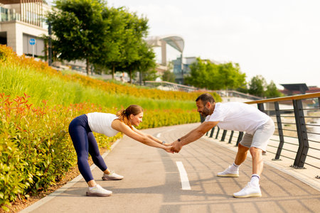 Two individuals enjoy an energetic workout on a bright, sunny day, surrounded by lush greenery, sharing a moment of fitness and joy.の写真素材