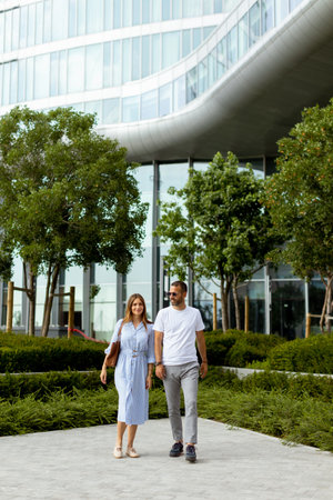 Two people walk hand in hand along a winding path, surrounded by greenery and contemporary...