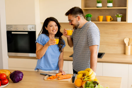 Couple shares delightful conversation and freshly squeezed juice in a bright kitchen filled with fresh produce and cheerful decor.の写真素材