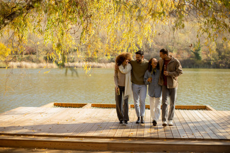 Warm sunlight filters through the trees as a group of friends strolls along a lakeside deck, sharing...