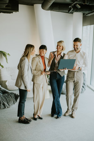 Four professionals gather in a stylish office space, sharing ideas and insights while standing near...