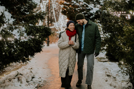 A Korean woman and a Caucasian man enjoy a cheerful winter walk, surrounded by glowing lights and...