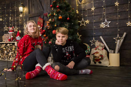 a handsome boy in a New Year's sweater sits with a girl at a decoratedの写真素材