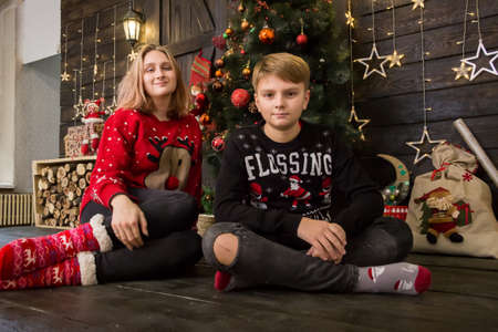 a handsome boy in a New Year's sweater sits with a girl at a decoratedの写真素材