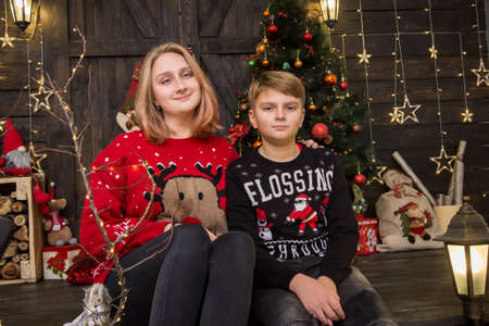 a handsome boy in a New Year's sweater sits with a girl at a decoratedの写真素材