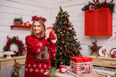 young blonde girl in a red wreath in a red christmas sweater in the christmas kitchenの写真素材