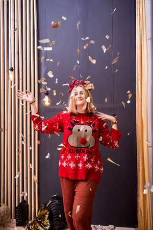 young blonde girl in a red wreath and a red Christmas sweater under flying sparklesの写真素材