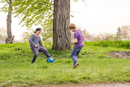 boy outdoors with ball playing football on grass in spring village