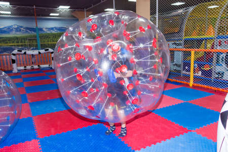 children, boys in the children's center play football while sitting in huge inflatable balls, hammer the ball into the goalの写真素材