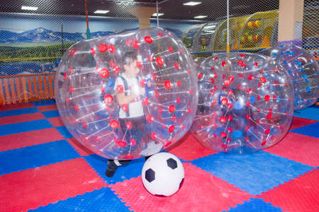 children, boys in the children's center play football while sitting in huge inflatable balls, hammer the ball into the goalの写真素材