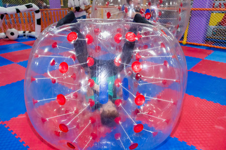 children, boys in the children's center play football while sitting in huge inflatable balls, hammer the ball into the goalの写真素材