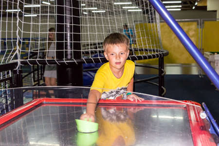 boy in a yellow t-shirt plays air hockey on the tableの写真素材