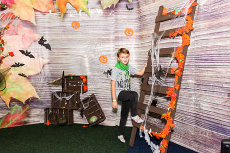 a boy in a children's center posing in an autumn photo zone, stairs, cobwebs, bats, wooden boxes, yellow leavesの写真素材