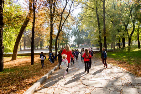 children in the autumn park on excursions go through a quest with a teacherの写真素材