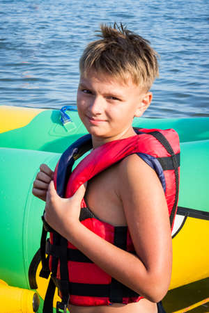 young boy in a red life jacket, summer at seaの写真素材