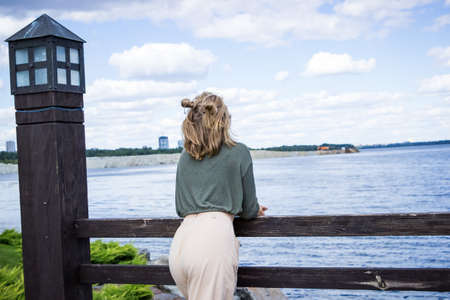 a girl stands on a wooden bridge near the river in summerの写真素材