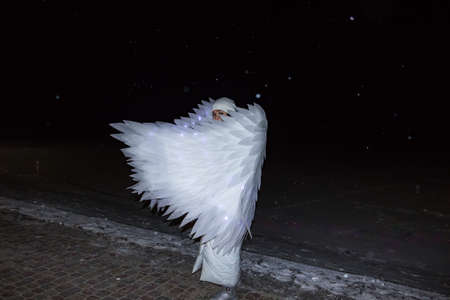 white angel girl under flying snow at night on the lake in winterの写真素材