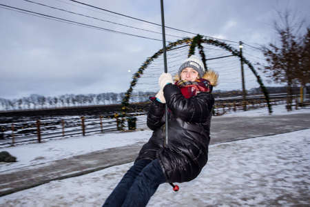 a girl rides a bungee in an amusement park in winterの写真素材