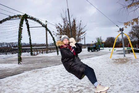 a girl rides a bungee in an amusement park in winterの写真素材