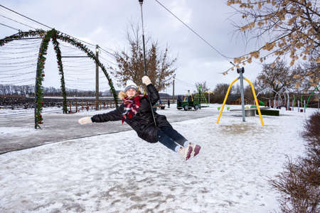 a girl rides a bungee in an amusement park in winterの写真素材