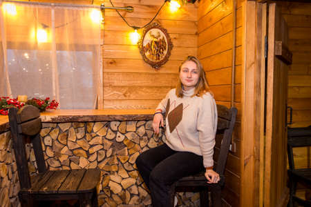 girl in a winter log cabin sitting by the windowの写真素材