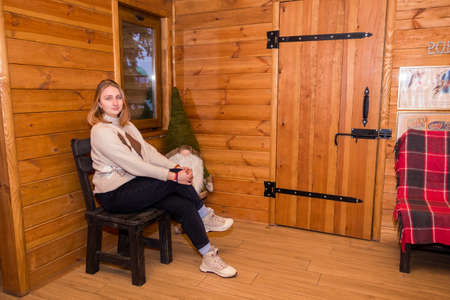 girl in a winter log cabin sitting by the windowの写真素材