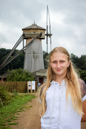 blond girl against the background of an old wooden millの写真素材