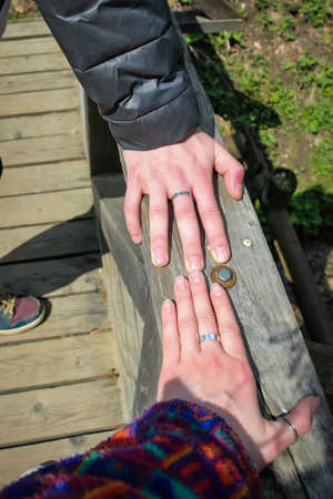 hands of a young man and a girl with rings on the railing of a wooden bridge, tourists in love, Carpathians, Western Ukraineの写真素材
