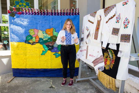a young girl in a traditional Ukrainian embroidered shirt near embroidered things and a map of Ukraineの写真素材