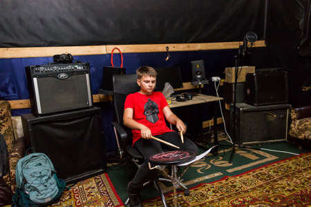 a young drummer plays drums, cymbals with sticks, sitting on a special chairの写真素材