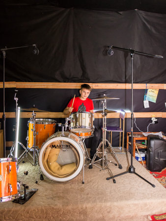 a young drummer plays drums, cymbals with sticks, sitting on a special chairの写真素材