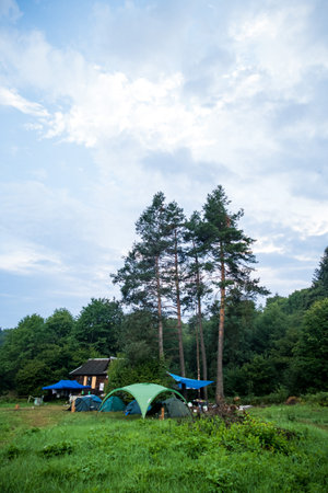 camping in the mountains with tents, log house, tourismの写真素材