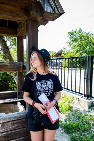 a beautiful girl in a black hat and a patriotic T-shirt near a wooden old well in the village,の写真素材